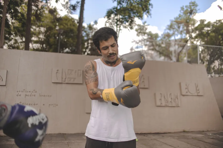 Praticante do The Rua treinando boxe com luvas na praça